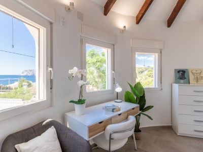 Luminoso despacho con vistas al mar, escritorio moderno y detalles decorativos.