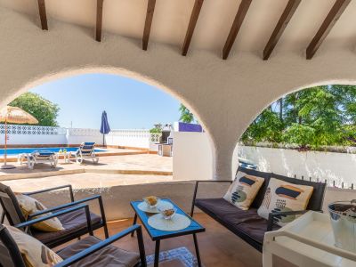 Porche cubierto con vistas a la piscina y al jardín, ideal para relajarse al aire libre.