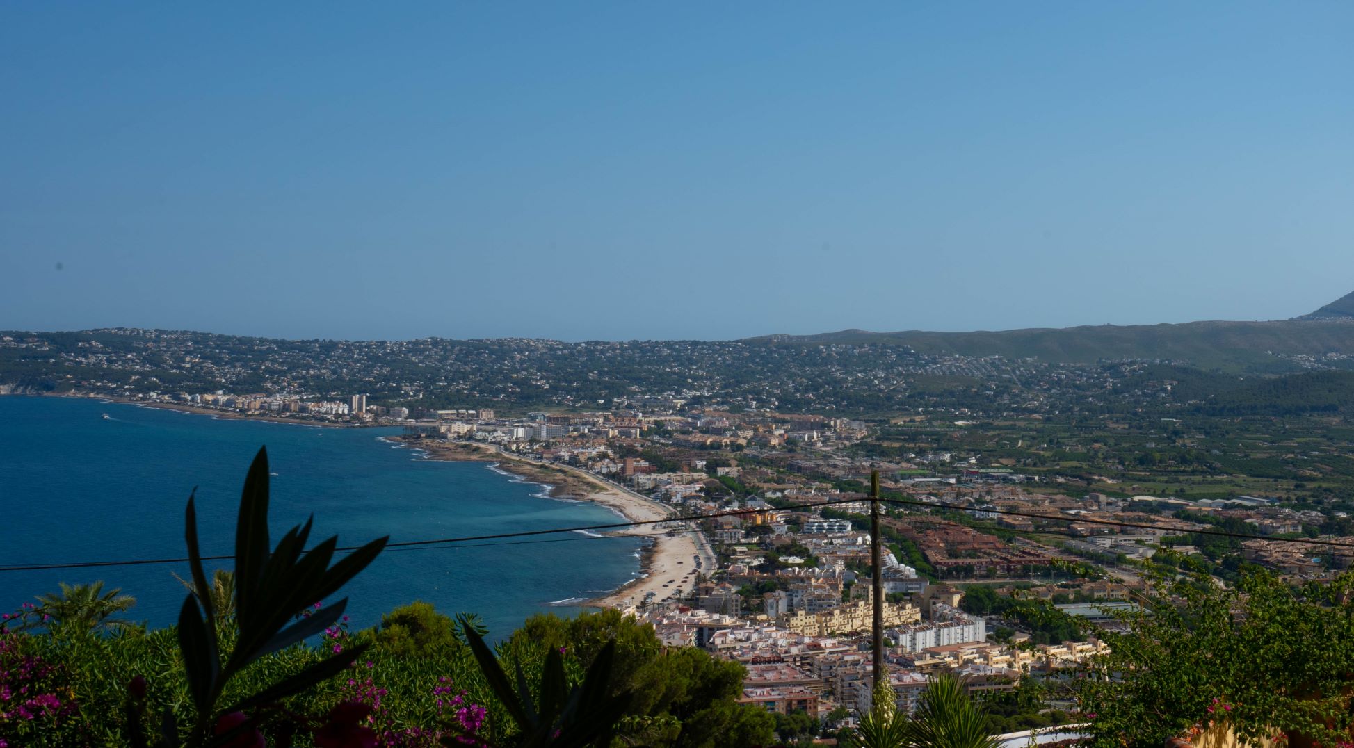Vista panorámica de la bahía de Jávea desde la parcela, con vegetación en primer plano.