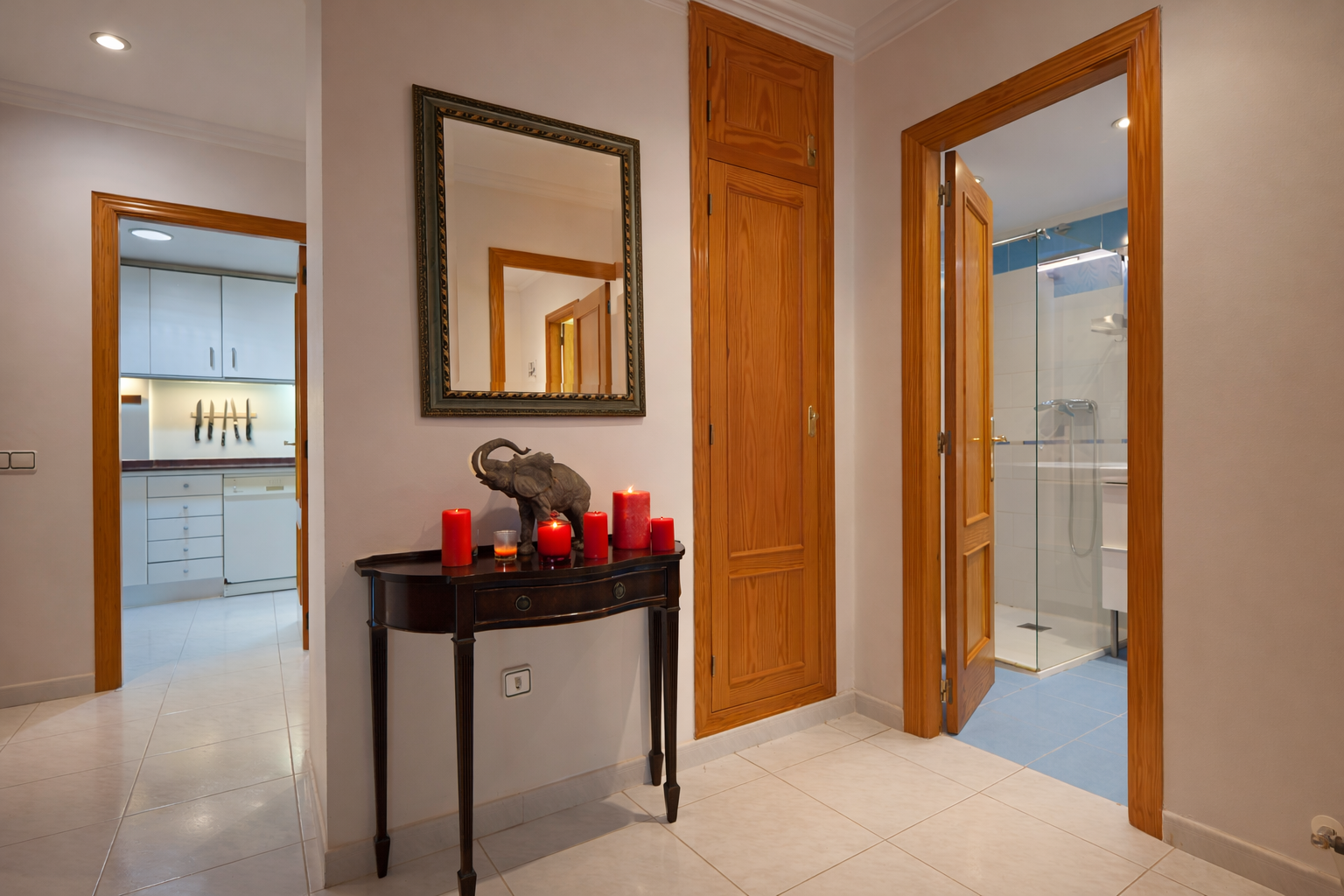 Detalle del recibidor con consola de madera, espejo y acceso al baño.