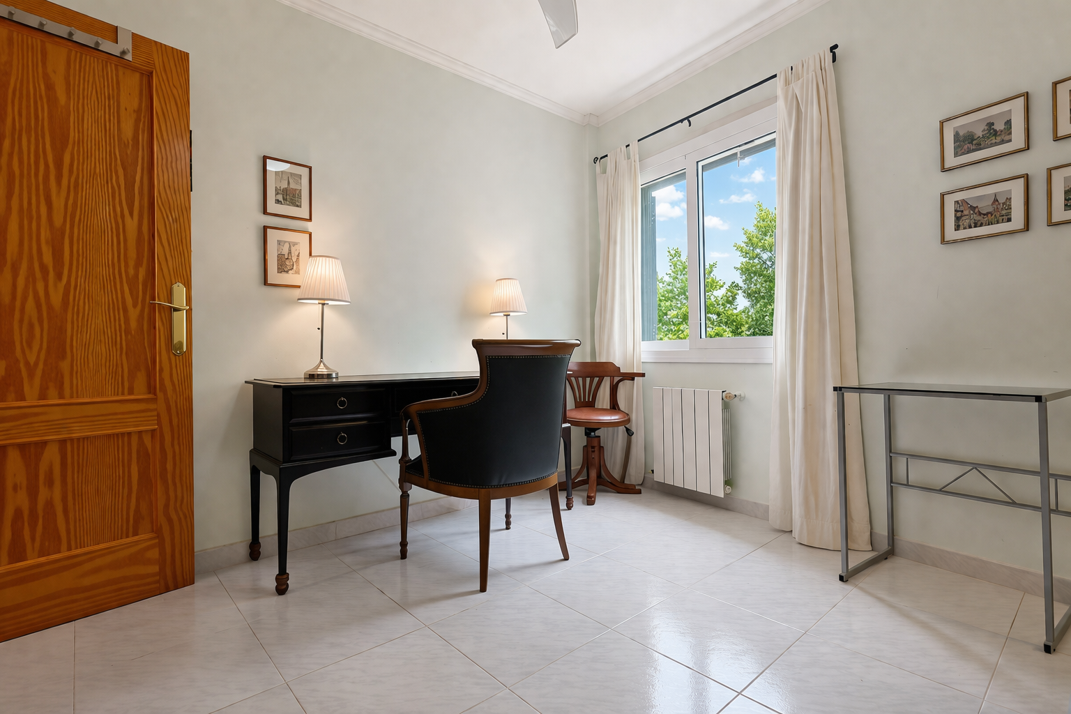 Habitación luminosa con escritorio clásico de madera oscura y silla tapizada, ideal para estudio o trabajo.