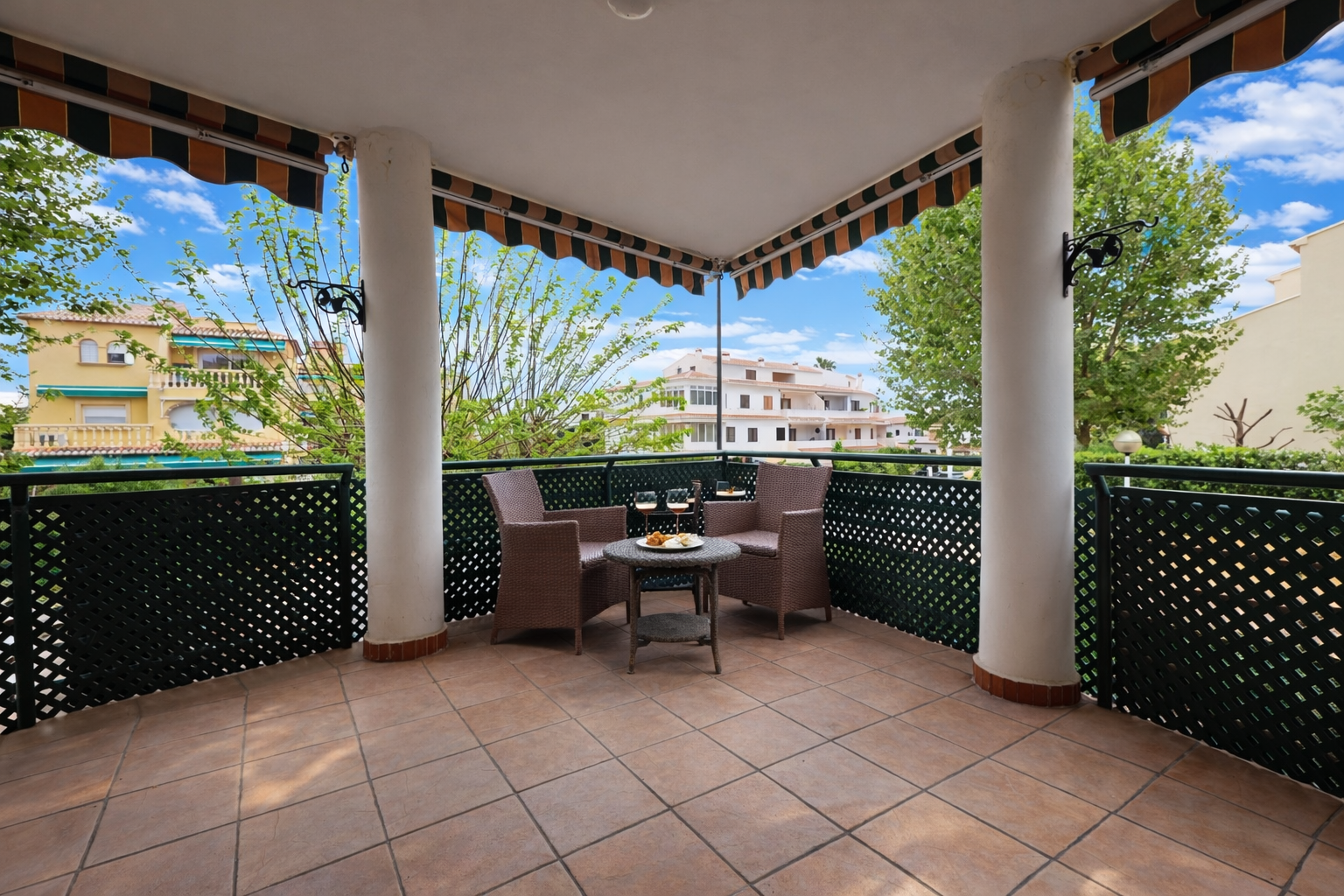 Terraza cubierta con suelo de baldosas y vistas a edificios residenciales.