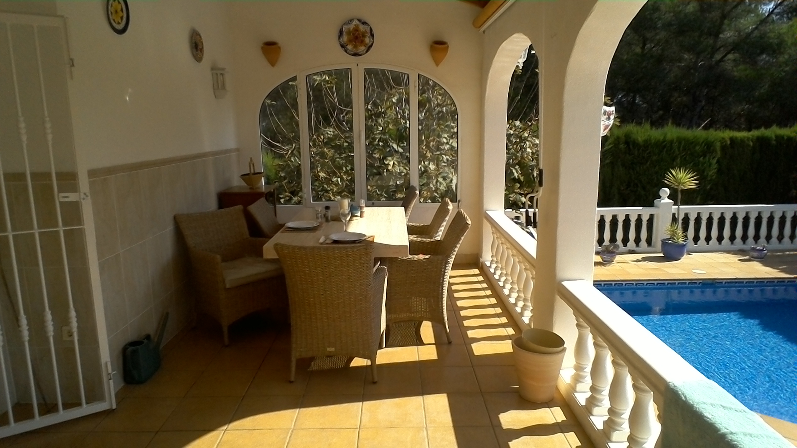 Comedor exterior cubierto con vistas a la piscina y jardín.