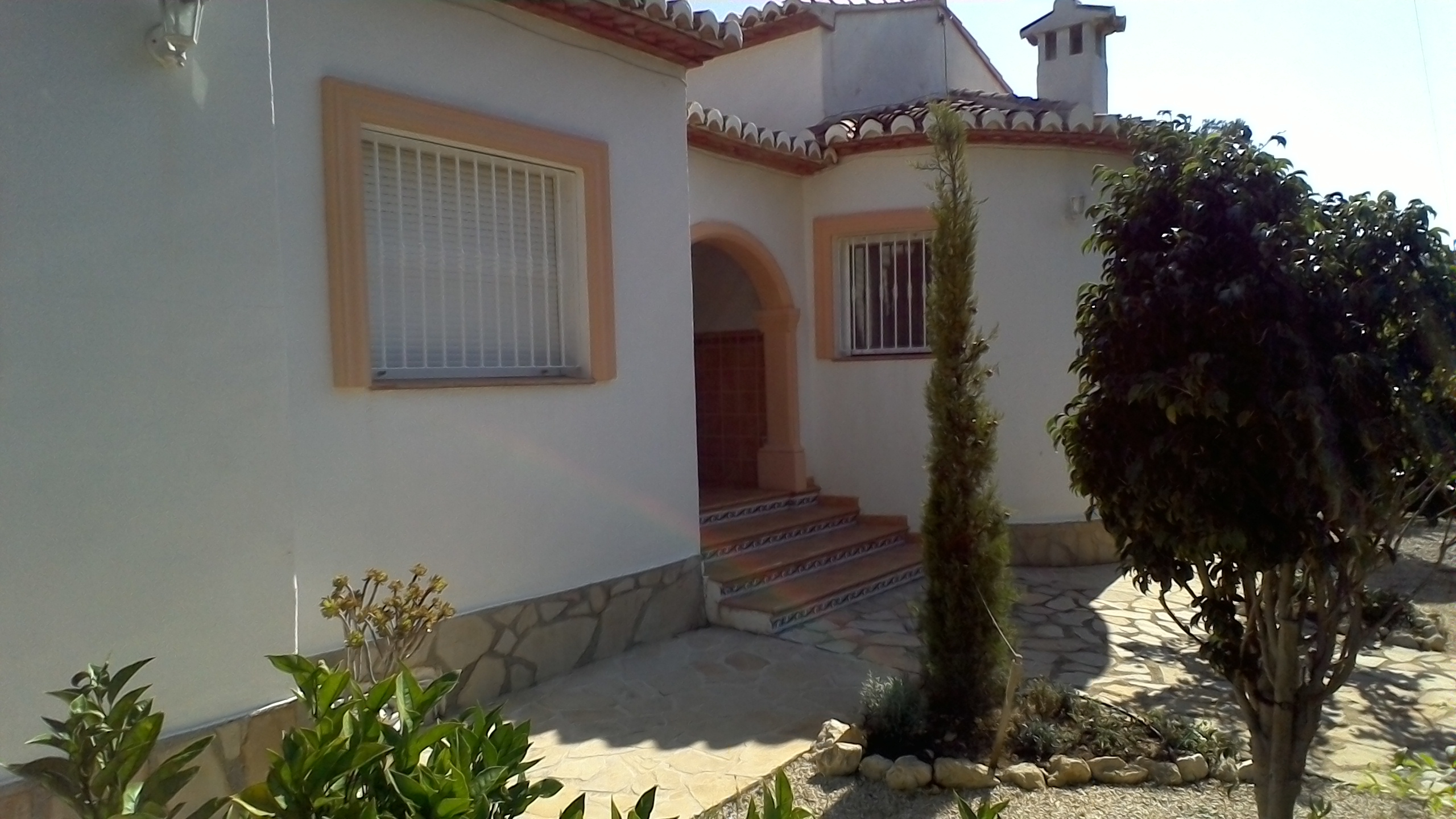 Fachada de villa con detalles en piedra y acceso escalonado con azulejos decorativos.