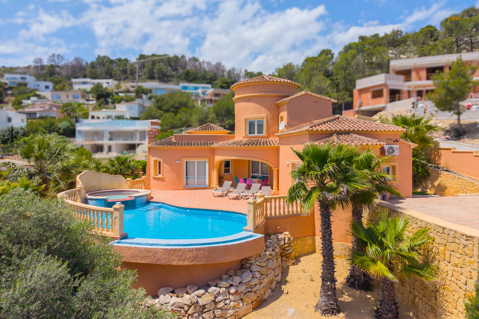 Vista aérea de la villa con piscina azul turquesa y jacuzzi integrado, rodeada de palmeras y jardines.