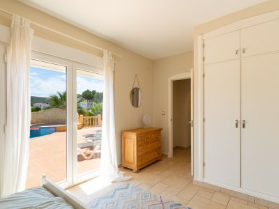 Dormitorio luminoso con acceso a la terraza y piscina. Armario empotrado y cómoda de madera.
