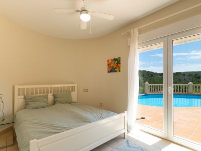 Dormitorio luminoso con acceso directo a la piscina y ventilador de techo.