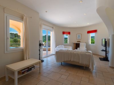 Salón luminoso con suelo de baldosas, sofá beige cubierto y vistas al exterior.