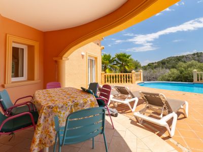 Terraza cubierta con mesa de comedor y acceso a la piscina en Jávea.