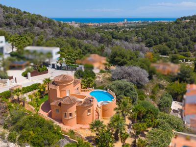 Vista aérea de la villa con piscina azul, rodeada de vegetación y con vistas al mar.