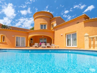 Vista de la fachada principal con piscina turquesa y terraza con tumbonas.