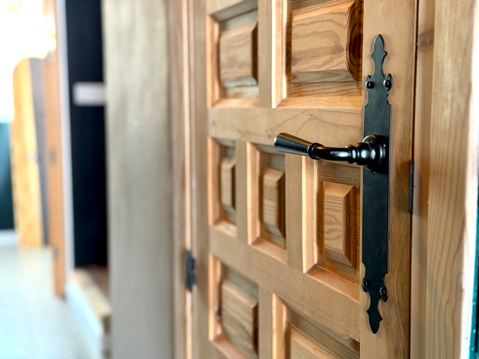 Detalle de puerta de madera con diseño en relieve y manija negra forjada.
