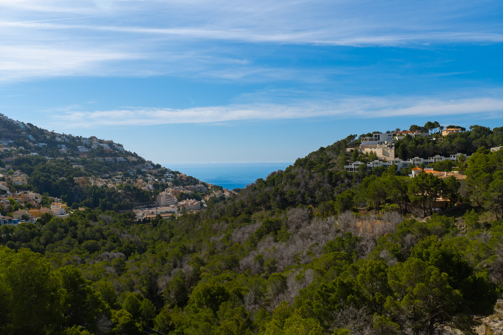 Vista panorámica de Altea Hills, mostrando edificios residenciales entre laderas verdes y el mar Mediterráneo en el horizonte bajo un cielo despejado. Vista panorámica de Altea Hills, mostrando edificios residenciales entre laderas verdes y el mar Mediterráneo en el horizonte bajo un cielo despejado.