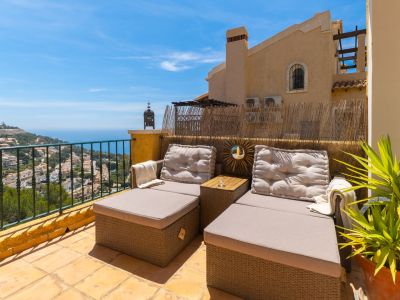 Amplia terraza con tumbonas de ratán, suelo de baldosas en tonos tierra y vistas panorámicas al mar Mediterráneo y las colinas de Altea.