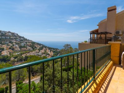 Amplia terraza exterior con barandilla verde forjada, suelo cerámico y vistas panorámicas a la urbanización Altea Hills y al azul intenso del Mediterráneo.