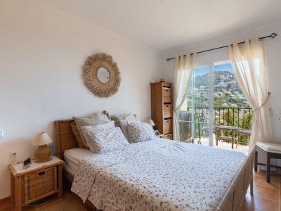 Luminoso dormitorio con cama y cabecero de mimbre, acceso directo a balcón privado. Ofrece suelos de gres y vistas panorámicas a la colina de Altea Hills.