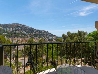 Terraza con barandilla de forja y mobiliario exterior, ofreciendo vistas panorámicas a la ladera de Altea Hills, cubierta de viviendas y vegetación, con el mar Mediterráneo al fondo.