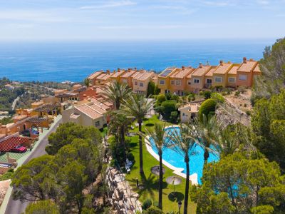 Vista aérea de un complejo residencial escalonado con piscina comunitaria, palmeras y vistas panorámicas al mar Mediterráneo.