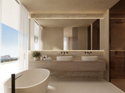 Baño principal con bañera de piedra exenta, doble lavabo y vistas panorámicas al mar a través de amplios ventanales.