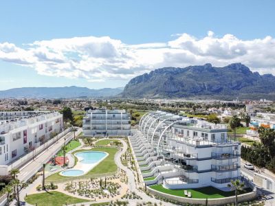 Vista aérea de un complejo residencial moderno con dos edificios blancos de diseño, piscinas comunitarias, jardines paisajísticos y parque infantil, con montañas al fondo.