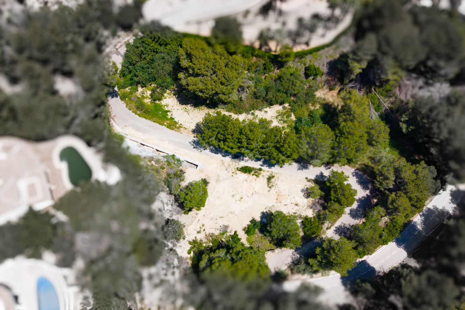 Vista aérea de parcela en Mar Azul, Jávea, mostrando terreno sin edificar rodeado de vegetación.
