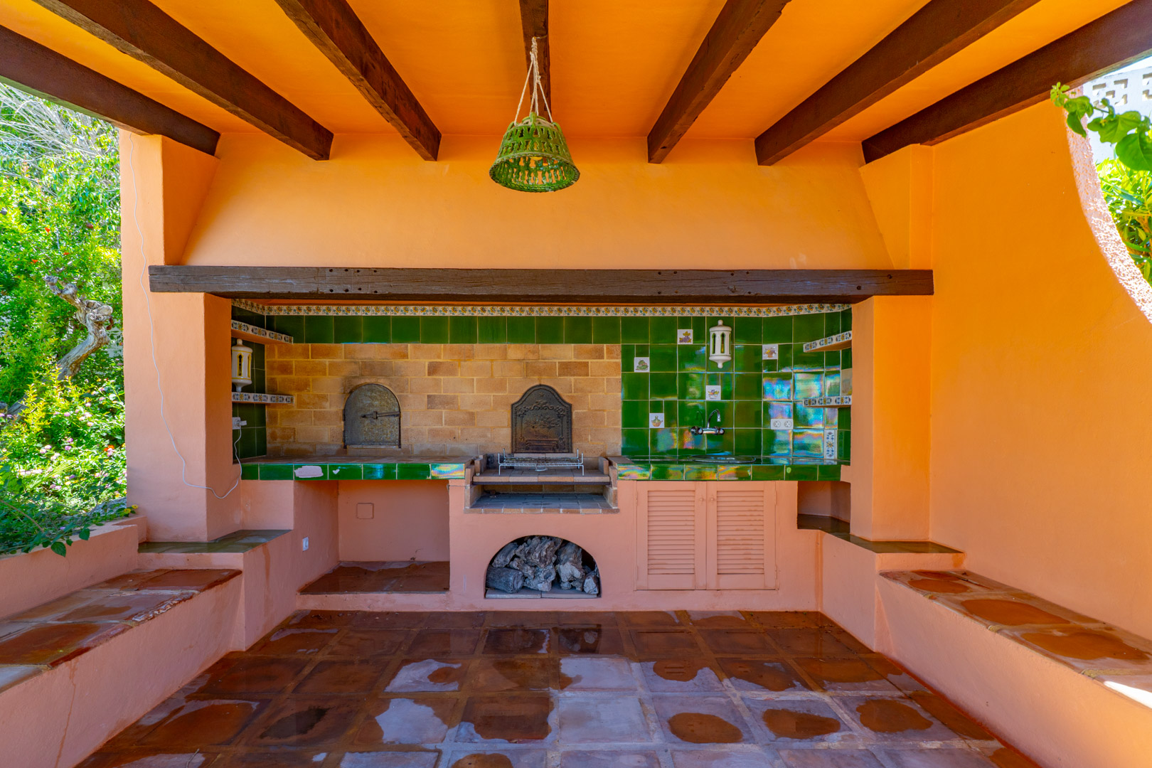 Barbacoa exterior con horno de leña y fregadero en terracota.
