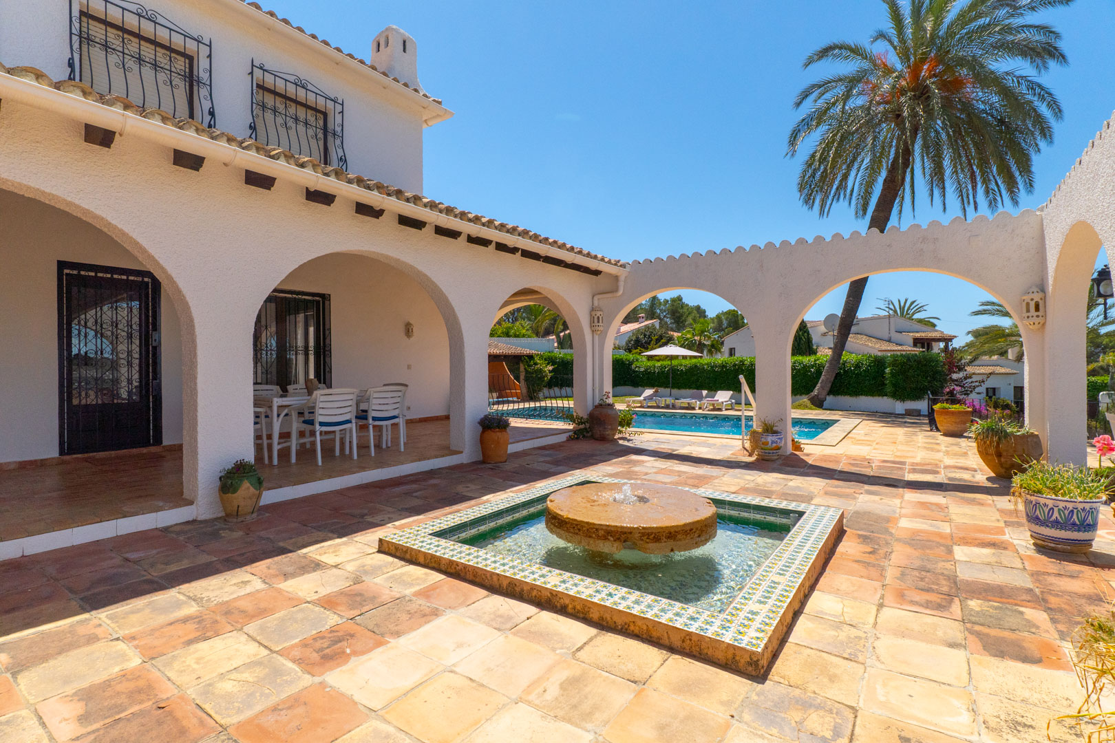 Patio con fuente de piedra y acceso a la piscina, en villa de Moraira.