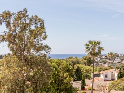 Vista panorámica desde la villa, mostrando el mar Mediterráneo en el horizonte, exuberante vegetación y casas residenciales con tejados de terracota.