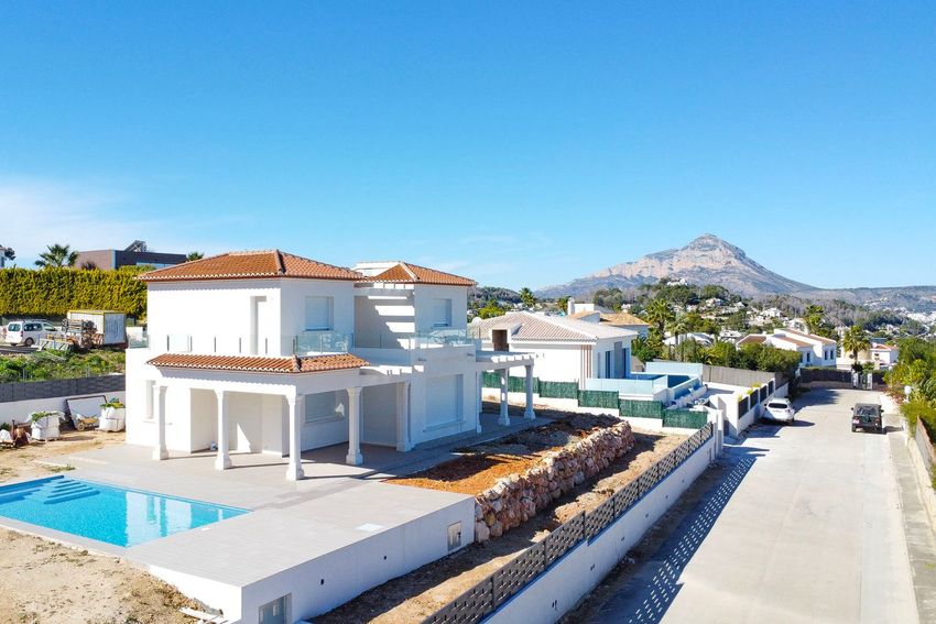 Vista aérea de la villa de obra nueva con piscina privada y terraza cubierta en planta baja. Se aprecian vistas a la montaña y la zona residencial circundante. Vista aérea de la villa de obra nueva con piscina privada y terraza cubierta en planta baja. Se aprecian vistas a la montaña y la zona residencial circundante.