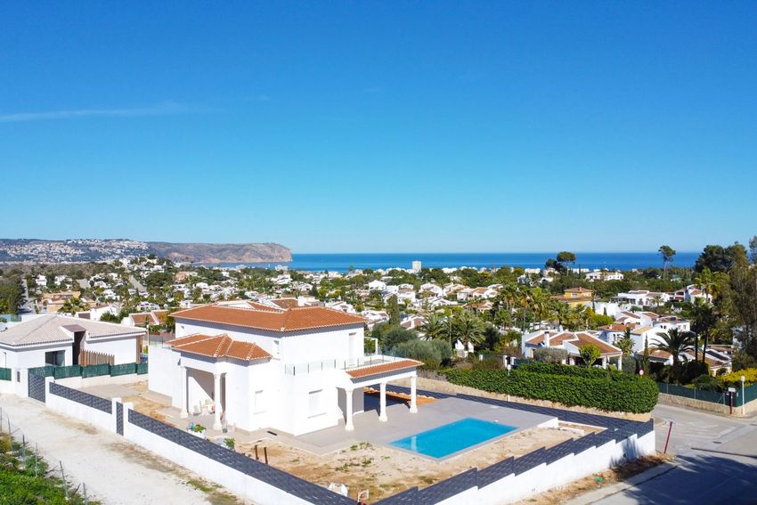 Vista aérea de la villa de obra nueva con piscina rectangular, terraza cubierta y amplias vistas al mar Mediterráneo y la costa de Jávea. Vista aérea de la villa de obra nueva con piscina rectangular, terraza cubierta y amplias vistas al mar Mediterráneo y la costa de Jávea.