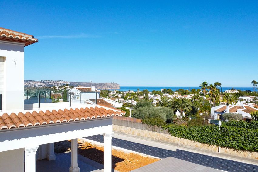 Vista panorámica al mar Mediterráneo y el Cabo de San Antonio, con tejados residenciales y exuberante vegetación. Un tejado de tejas tradicional se aprecia en primer plano. Vista panorámica al mar Mediterráneo y el Cabo de San Antonio, con tejados residenciales y exuberante vegetación. Un tejado de tejas tradicional se aprecia en primer plano.