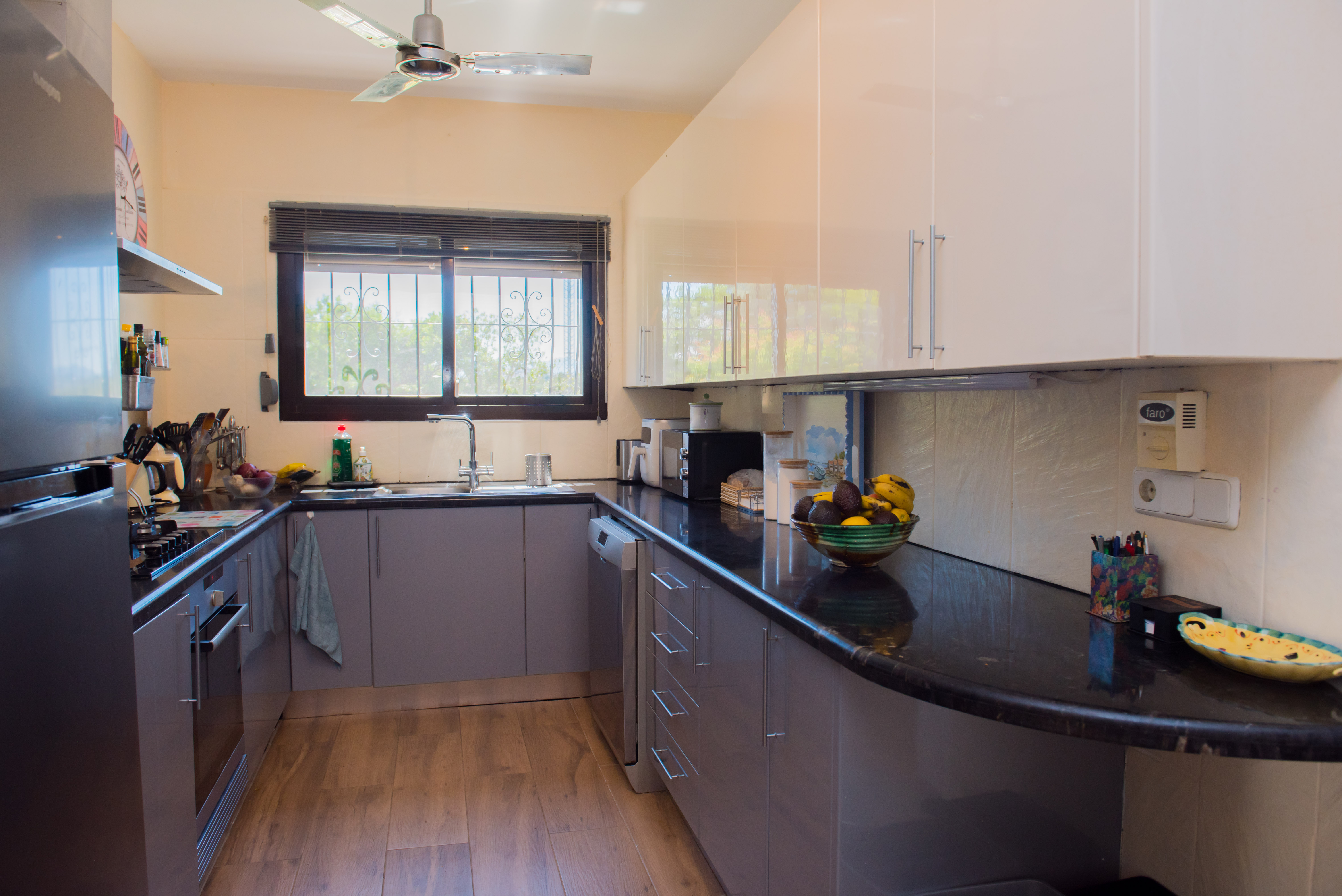 Cocina con encimeras de granito negro y muebles grises.