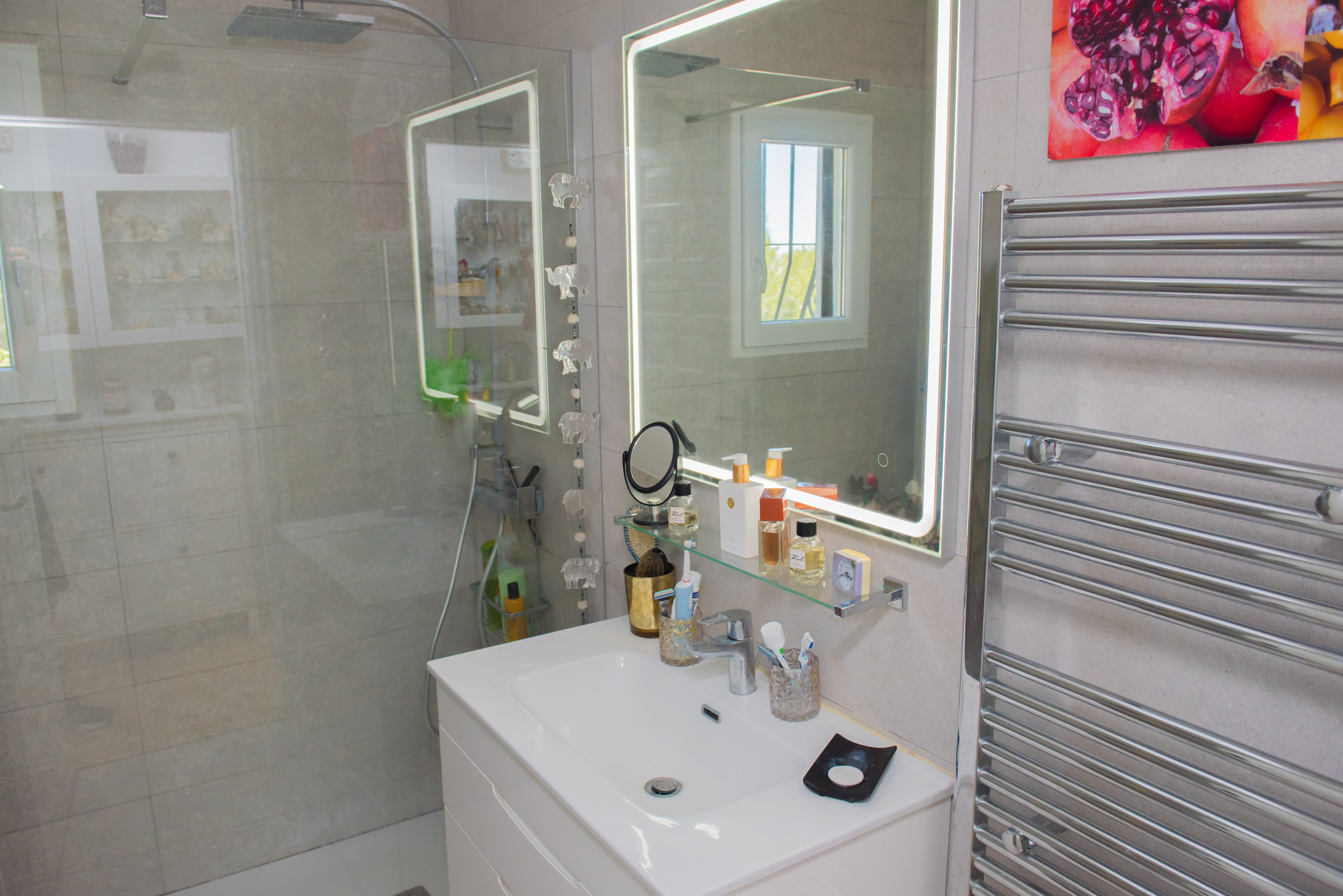 Detalle del baño con lavabo blanco, espejo iluminado y toallero cromado.