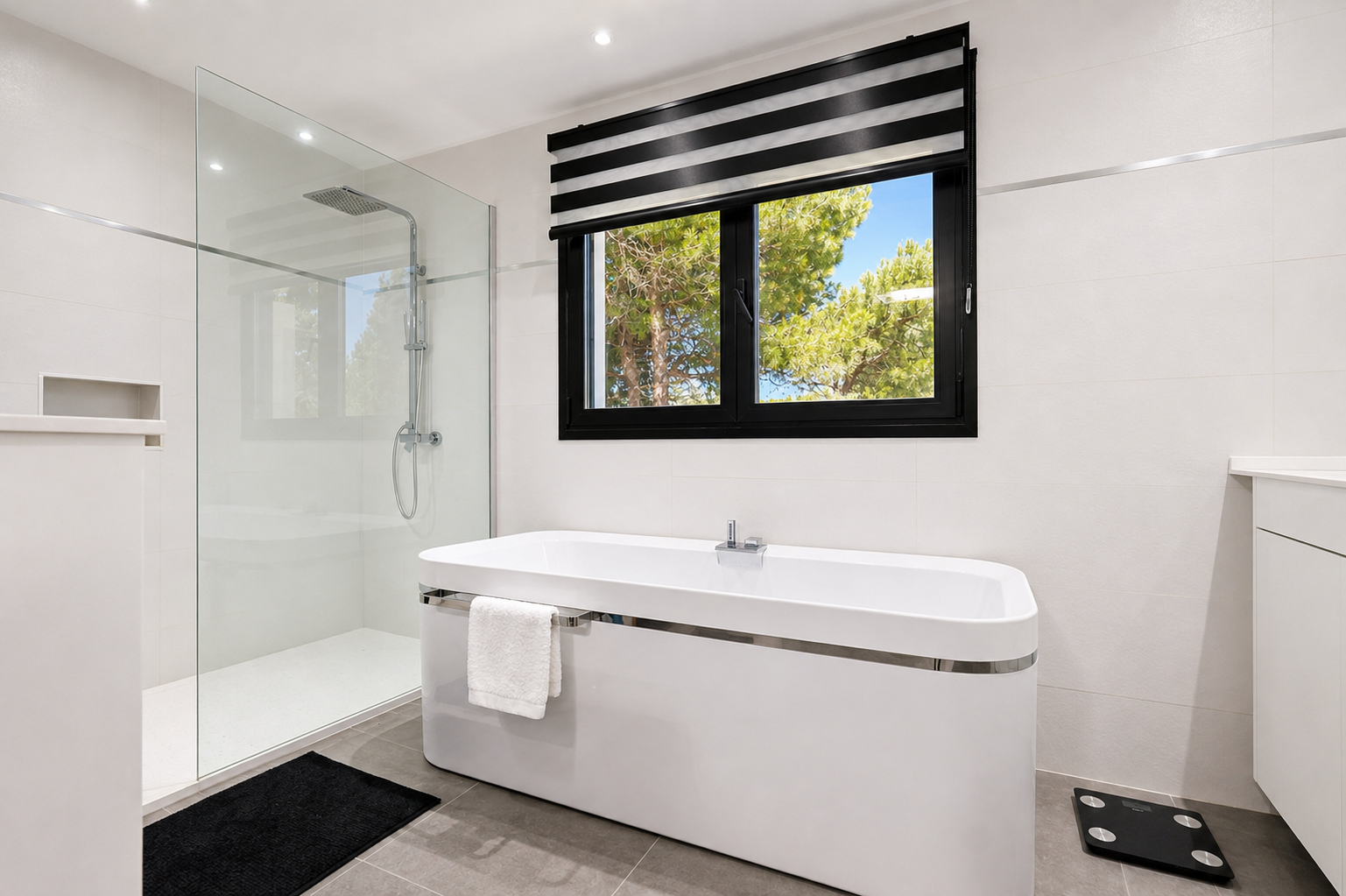 Elegante baño con bañera exenta, ducha de cristal y ventana con vistas al exterior.