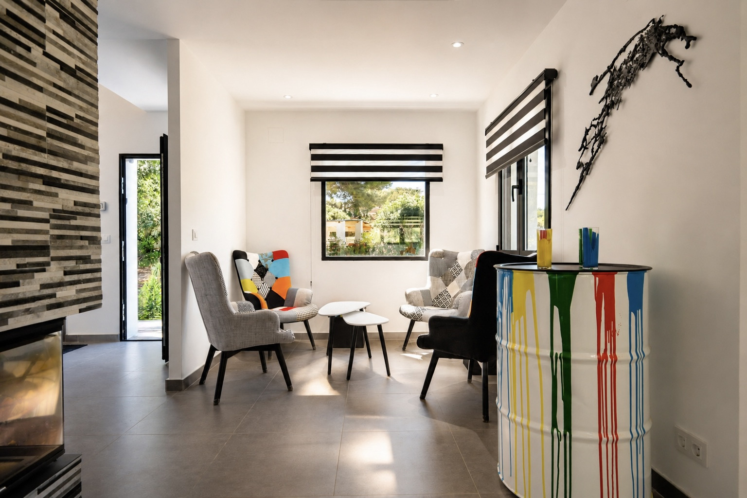 Sala de estar con decoración moderna: sillones de diseño, mesa auxiliar y barril decorativo con pintura.