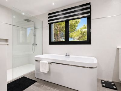 Elegante baño con bañera exenta, ducha de cristal y ventana con vistas al exterior.