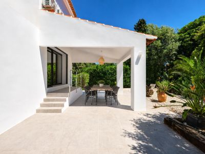 Naya cubierta con mesa de comedor, rodeada de jardines exuberantes y acceso a la villa.