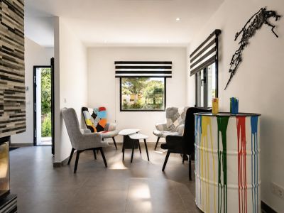 Sala de estar con decoración moderna: sillones de diseño, mesa auxiliar y barril decorativo con pintura.