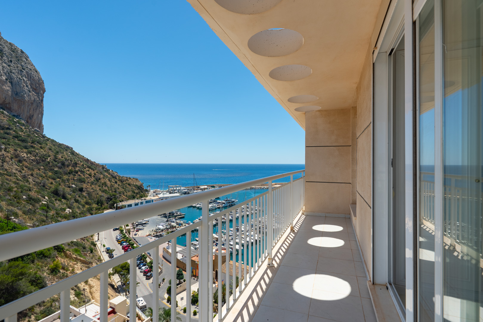 Amplia terraza con vistas directas al puerto deportivo de Calpe, el mar Mediterráneo y el icónico Peñón de Ifach, con suelo de baldosas y puertas correderas de cristal.