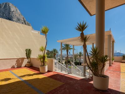 Terraza exterior comunitaria con pavimento amarillo y terracota, plantas mediterráneas en macetas y vistas directas al Peñón de Ifach y al puerto deportivo de Calpe.