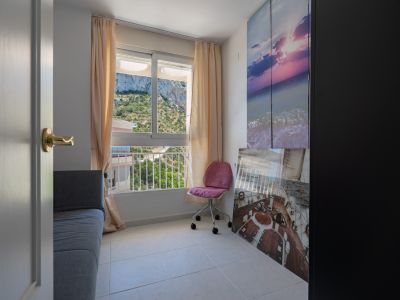 Dormitorio auxiliar o despacho con vistas a la montaña, equipado con sofá, silla de oficina y suelo de baldosas claras. Decorado con arte temático marino y armario oscuro.