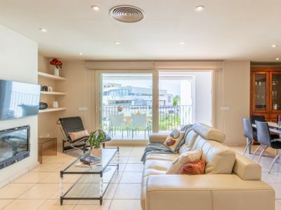 Amplia sala de estar con sofá de cuero crema, chimenea integrada y TV mural. Grandes puertas correderas conectan con una terraza privada, aportando luz natural y fluidez al espacio.
