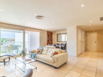 Amplio salón-comedor de planta abierta con sofá de cuero crema y acceso directo a una terraza privada, inundado de luz natural y con suelo de gres claro.
