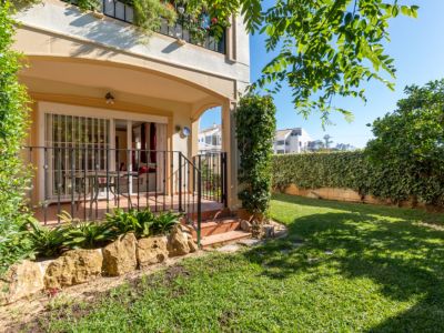 Amplio jardín privado con césped bien cuidado, rodeado de setos verdes. Incluye una terraza cubierta con acceso directo al interior, ideal para relajarse al aire libre.
