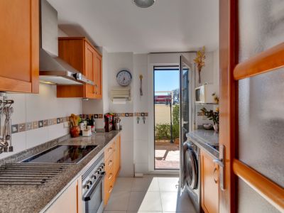 Cocina funcional con armarios de madera clara, encimeras de granito y electrodomésticos de acero inoxidable. Ofrece acceso directo a un patio exterior.