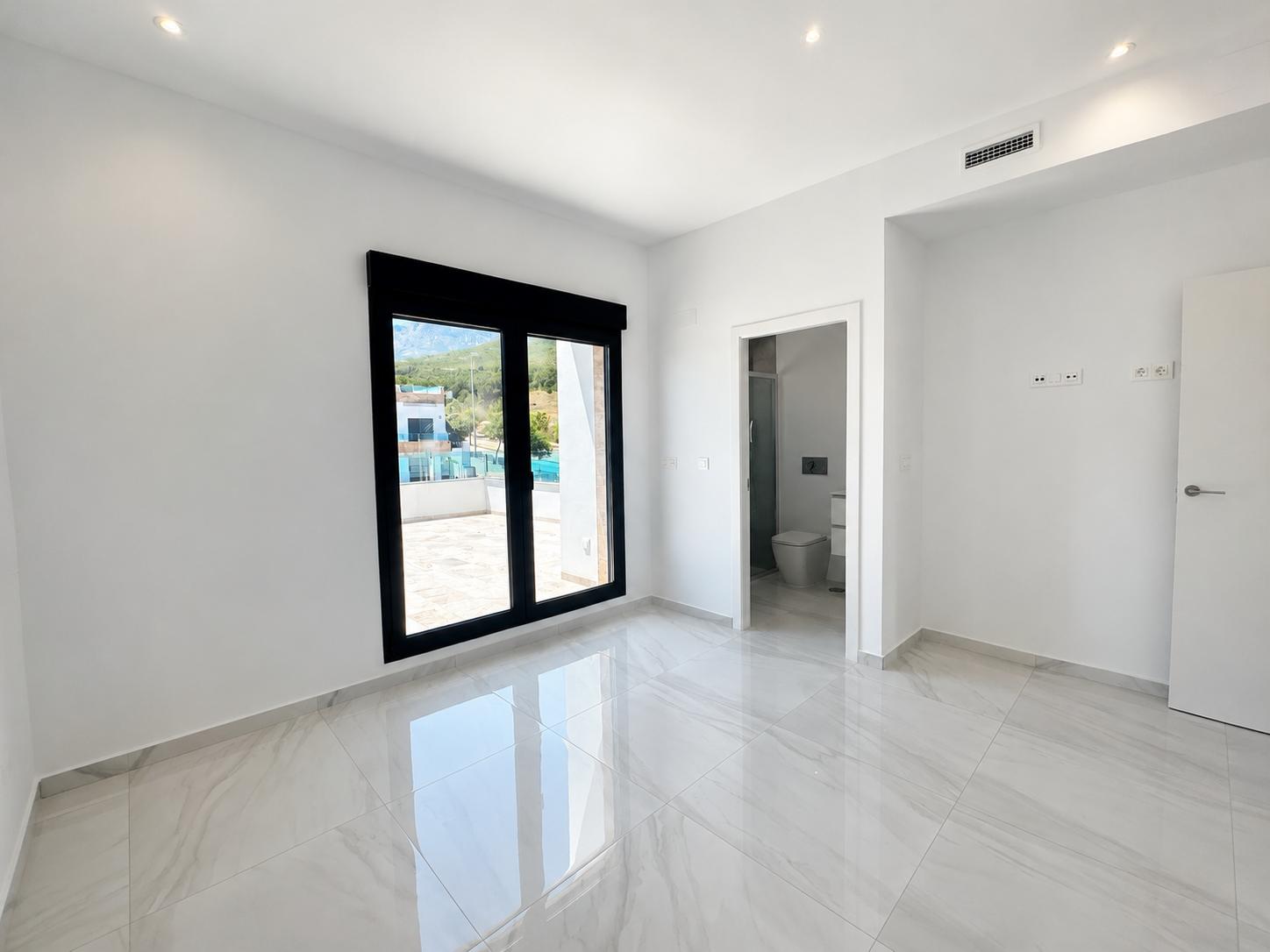 Amplio dormitorio con suelo de gres porcelánico brillante, acceso directo a la terraza exterior y baño en suite. Incluye iluminación empotrada y preinstalación de aire acondicionado.