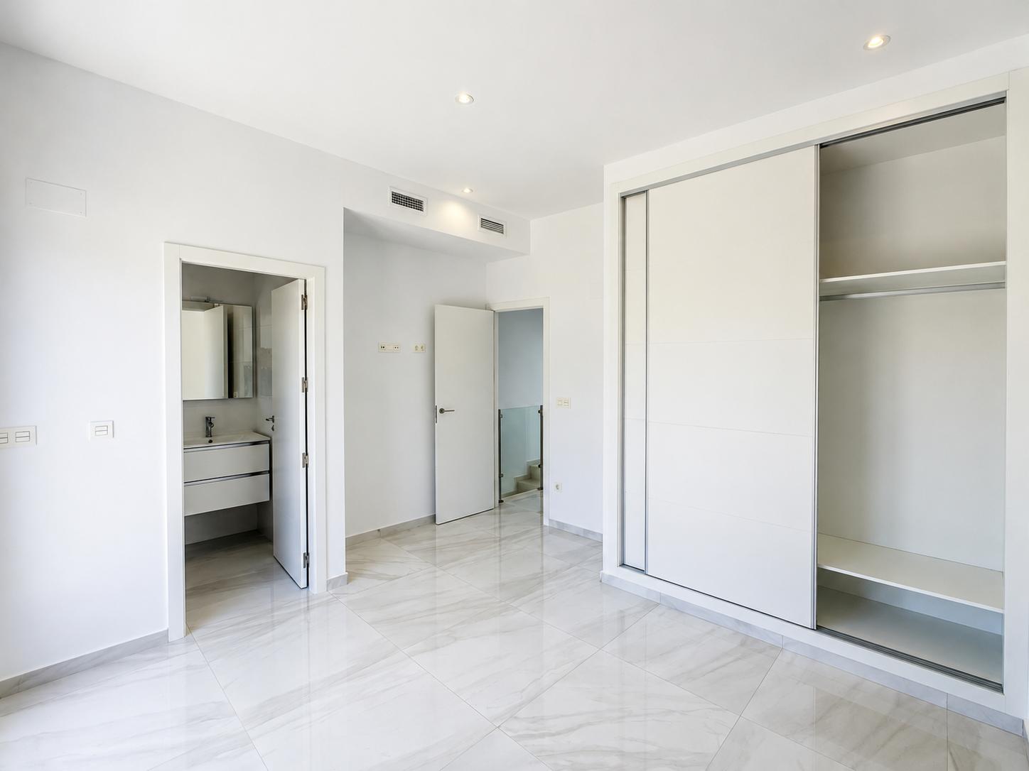 Dormitorio luminoso con suelo de gres porcelánico y armario empotrado de puertas correderas. Incluye acceso directo a un baño en suite y climatización por conductos.