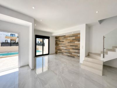 Amplia sala de estar con suelo porcelánico, pared decorativa de paneles efecto madera y acceso directo a la piscina privada. Escalera moderna con barandilla de cristal.