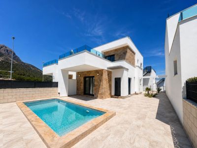 El exterior de la villa moderna exhibe una piscina rectangular privada y una amplia terraza de baldosas claras. Fachadas blancas con piedra natural y barandillas de cristal enmarcan vistas a la montaña.