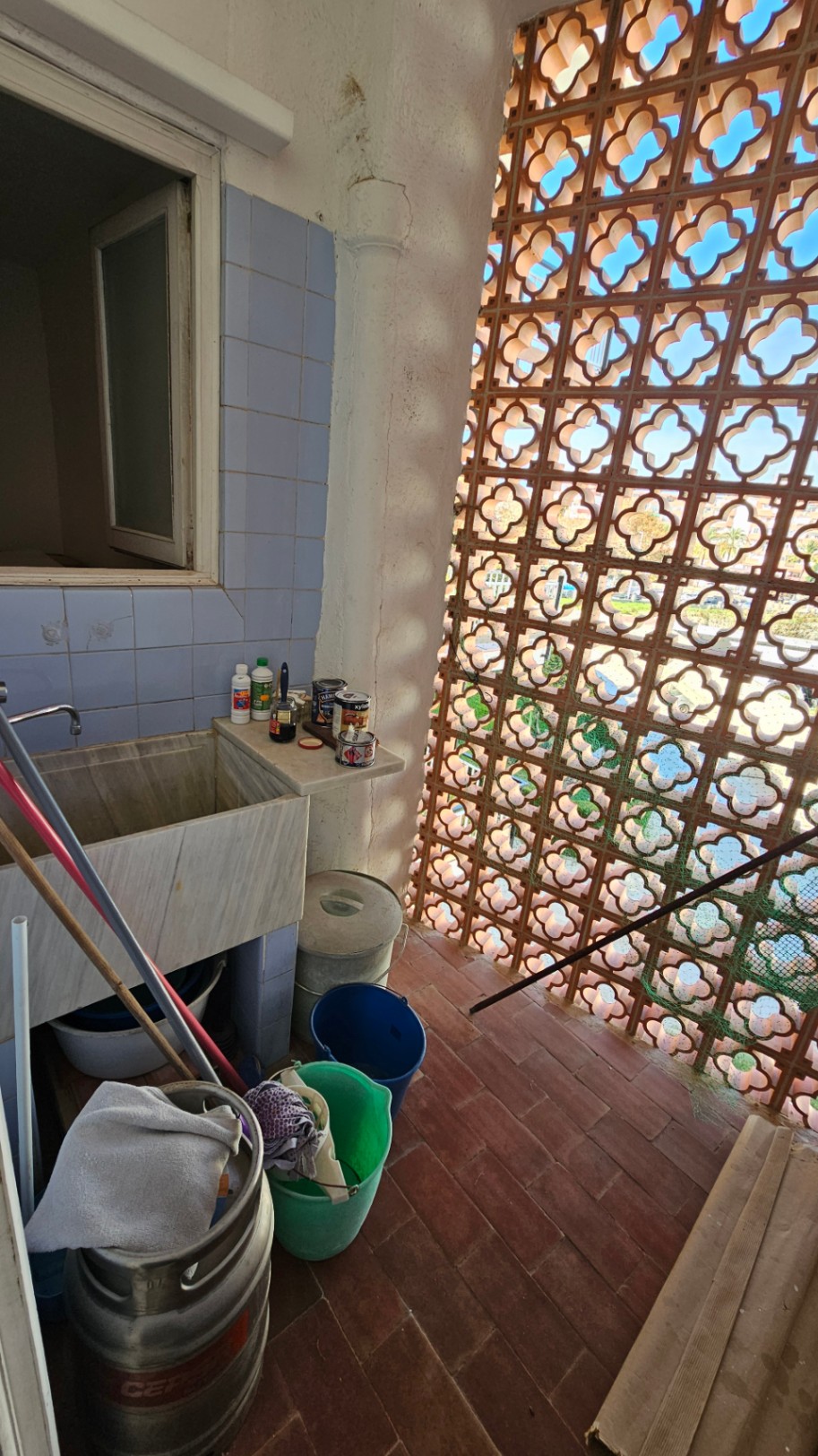 Zona de servicio con un gran lavadero de mármol, azulejos azules y celosía de terracota que filtra la luz natural. Espacio con potencial de reforma.